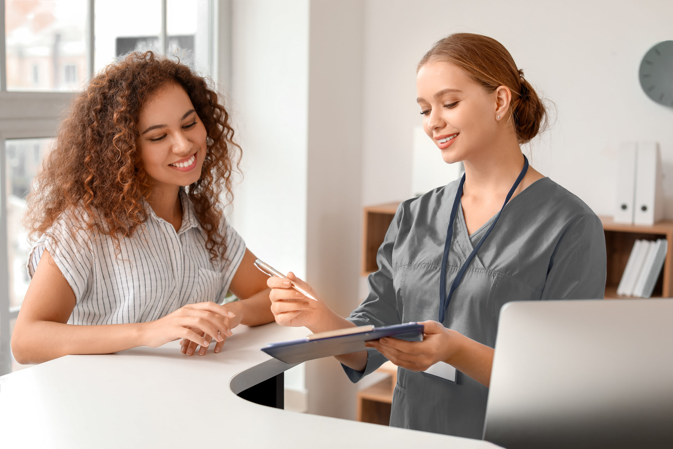 Young female receptionist working with patient in clinic
