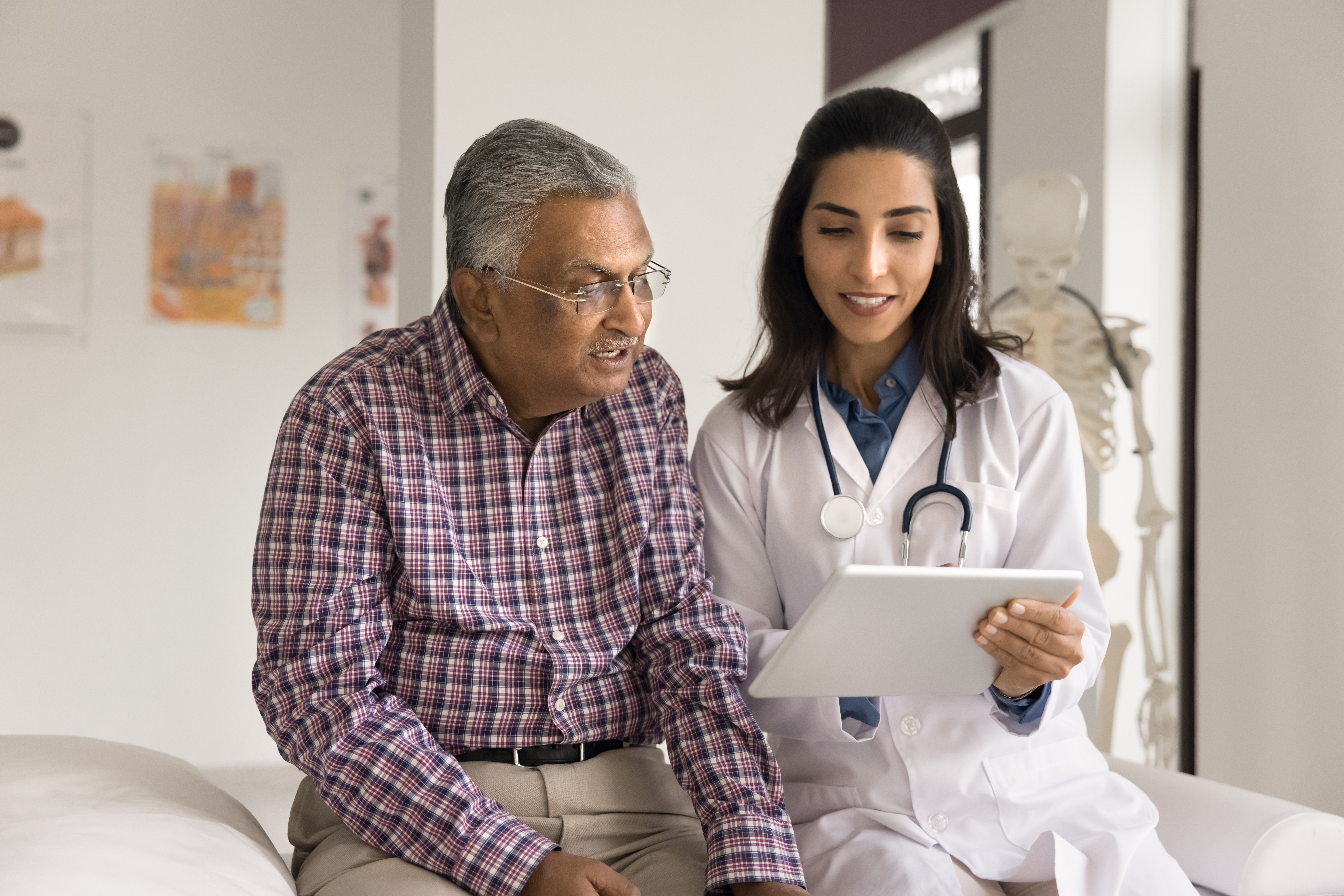 Positive young Indian doctor woman showing electronic content on tablet